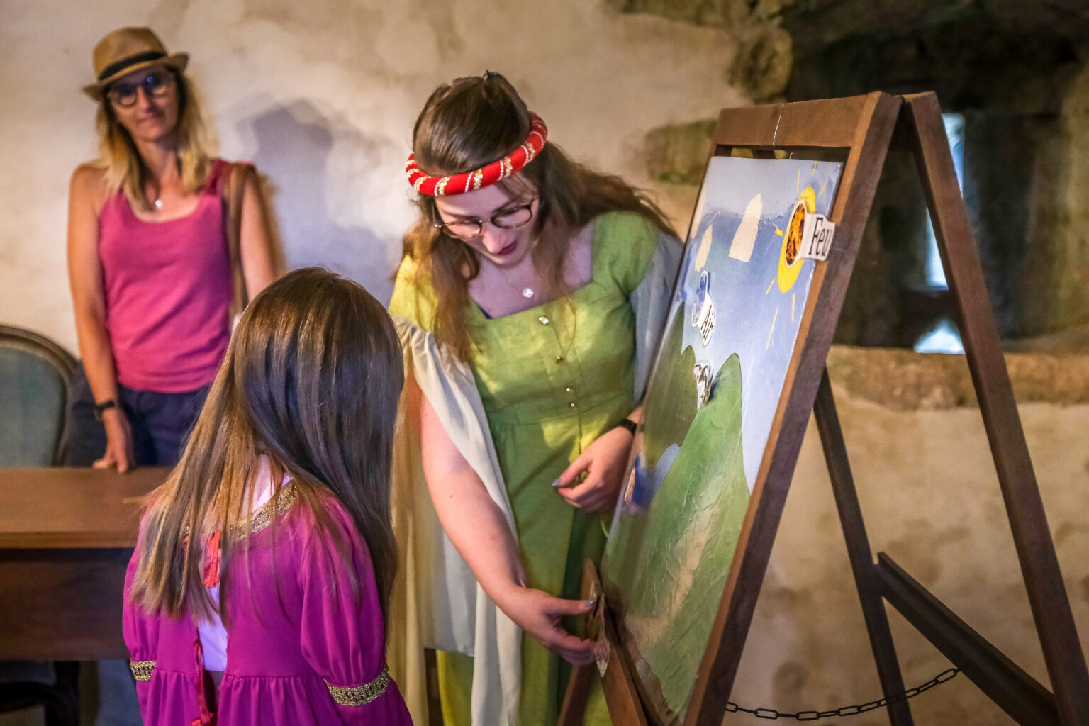 Jeune enfant et guide costumée participant à un atelier médiéval à la Tour du Viala-du-Pas-de-Jaux.