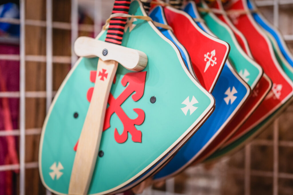 Boucliers et épées en bois inspirés du Moyen Âge exposés dans la boutique de la Tour du Viala-du-Pas-de-Jaux.