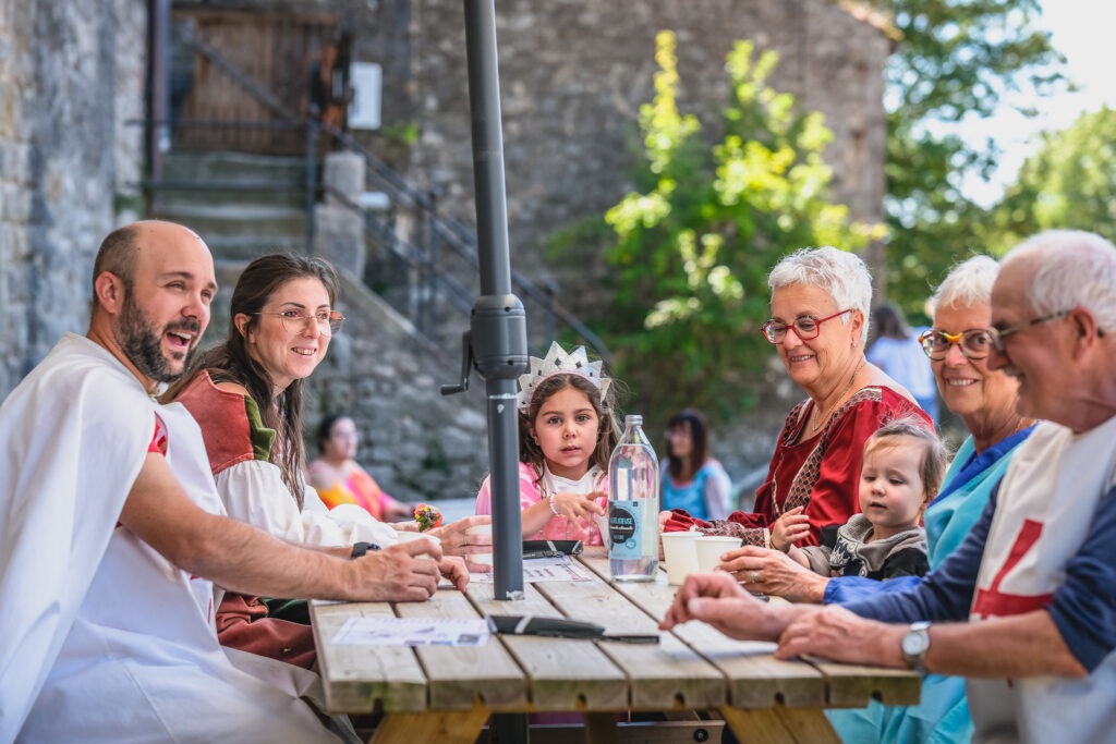 Famille costumée partageant un moment convivial autour d’une table à la Tour du Viala-du-Pas-de-Jaux.