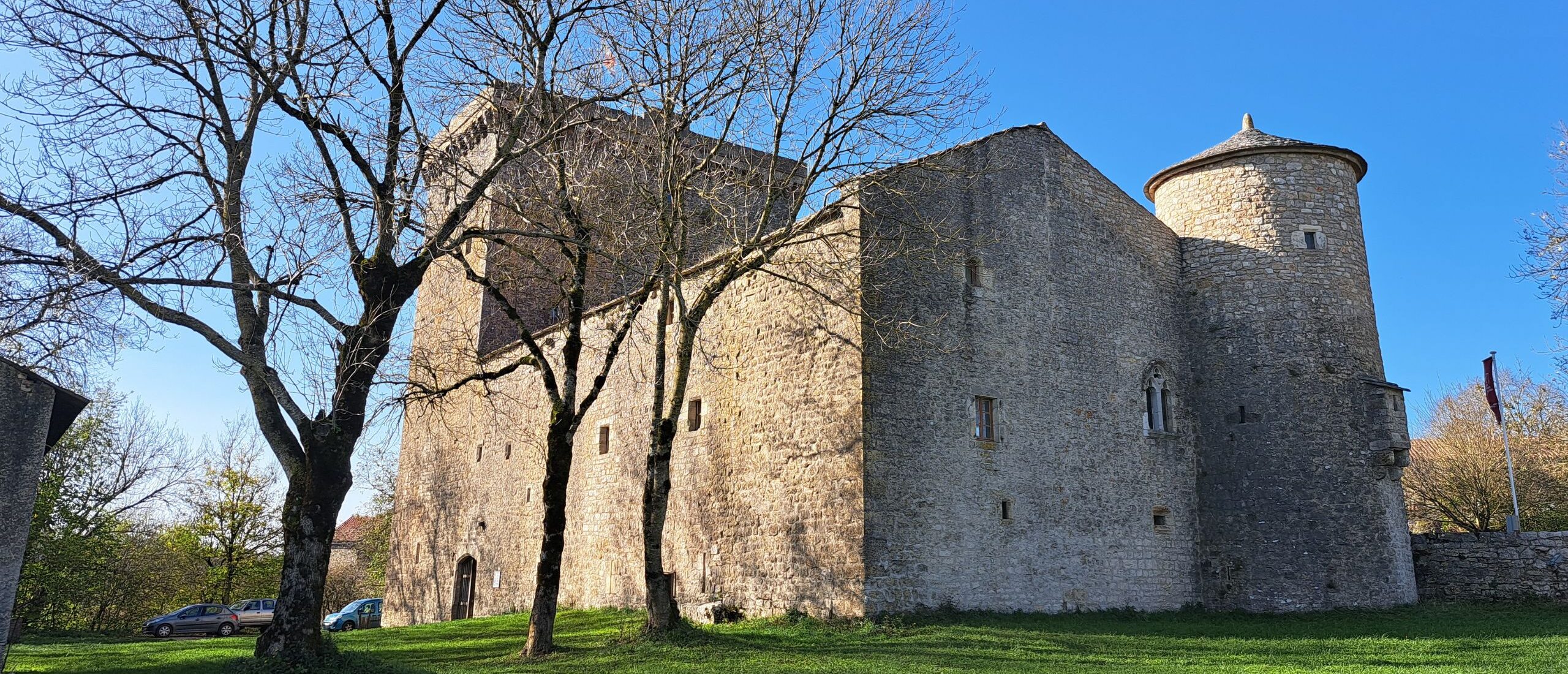Tour médiévale du Viala-du-Pas-de-Jaux entourée d’arbres dénudés et d’un ciel bleu hivernal.