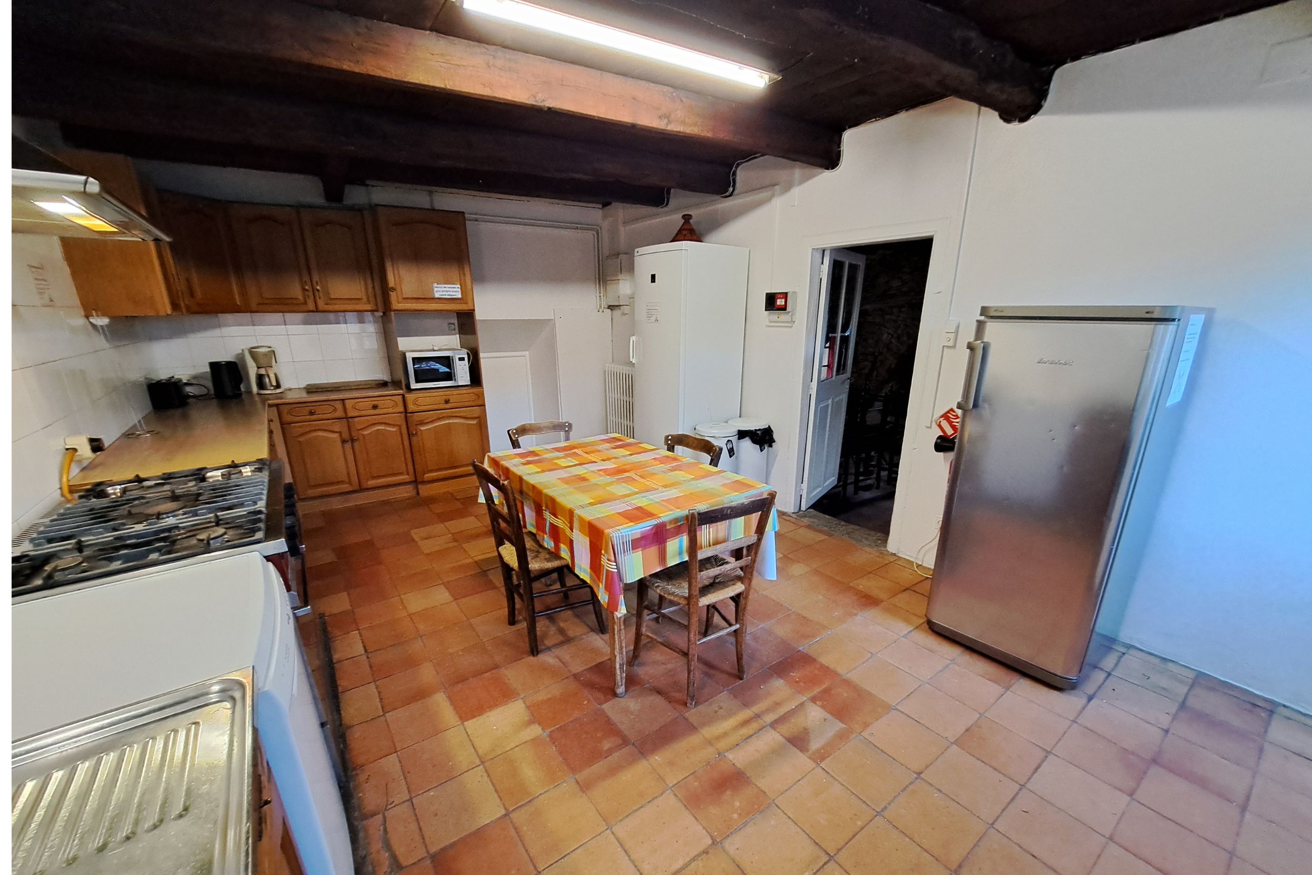 Cuisine équipée avec large plan de travail, table centrale, frigo et four du gîte d’étape de la Tour du Viala‑du‑Pas‑de‑Jaux.